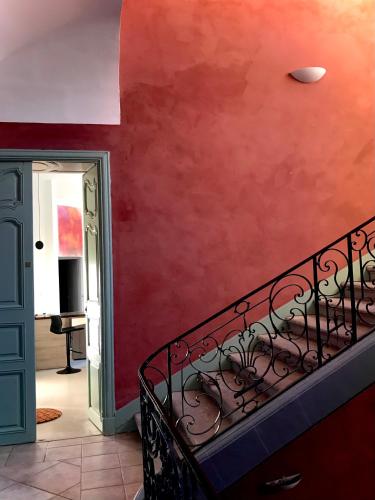 - un escalier dans une pièce dotée d'un mur rouge dans l'établissement Appartement à la Roquette, dans l'Hotel de Divonne, classé., à Arles
