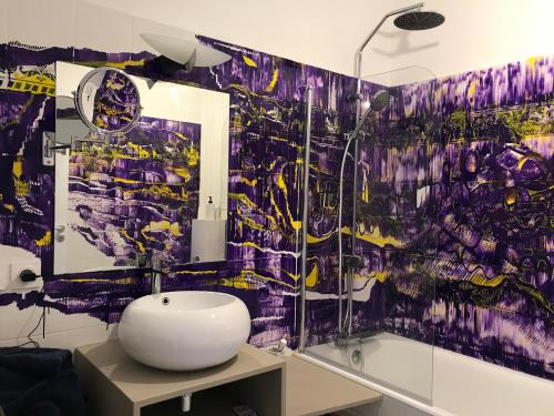 La salle de bains est pourvue d'un lavabo et d'un mur coloré. dans l'établissement Appartement à la Roquette, dans l'Hotel de Divonne, classé., à Arles