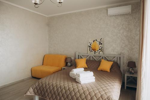 a bedroom with a bed and an orange chair at Три Слона in Zatoka
