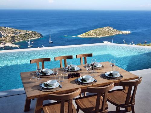 - une table en bois avec des chaises et une vue sur l'océan dans l'établissement Etheria Luxury Villas & Suites, à Agios Nikolaos