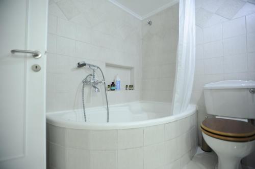 a white bathroom with a tub and a toilet at Sea & City views, Aspa’s apartment in Thessaloniki