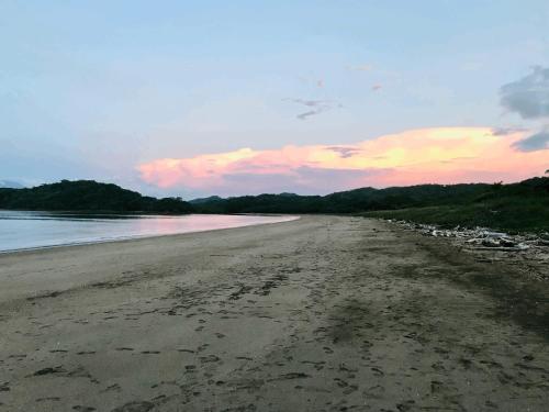 a sandy beach with a sunset in the background at Nandel Beach Resort in La Cruz