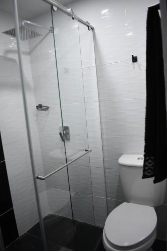 a bathroom with a toilet and a glass shower at Hostel Boutique Nido de Loros in Medellín