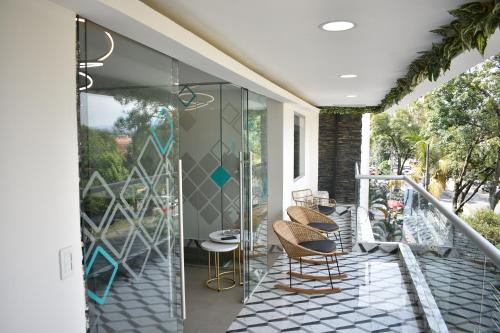 eine Terrasse mit Stühlen und Tischen auf dem Balkon in der Unterkunft Hostel Boutique Nido de Loros in Medellín