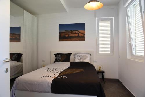 1 dormitorio con 1 cama y 2 ventanas en Residence Il Piviere app 7 with private garden, en Calambrone