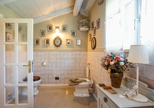 a bathroom with a toilet and a vase of flowers at The Lake House in Viverone