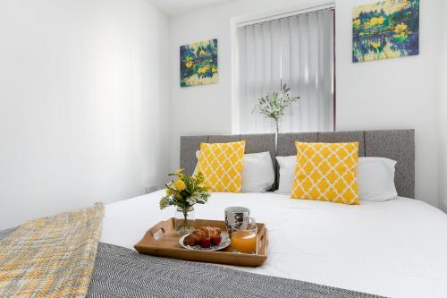 a bed with a tray of fruit and orange juice at KVM - City Apartments in Peterborough