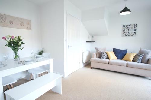 a white living room with a couch and a table at Bank Side House by KVM Stays in Peterborough