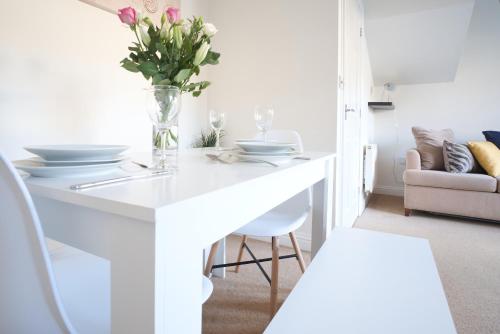 a white dining room table with a vase of flowers at Bank Side House by KVM Stays in Peterborough