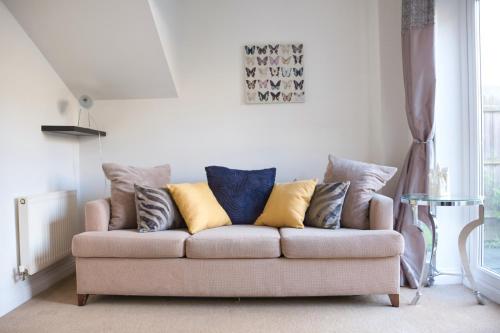 a couch with pillows on it in a living room at Bank Side House by KVM Stays in Peterborough