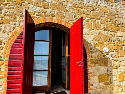 a red door in a brick building with a window at LaChiusa Tuscany in Montefollonico