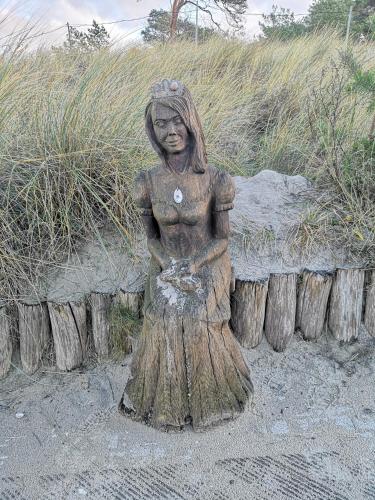 a statue of a woman sitting on some logs at Fewo Seepferdchen in Zempin