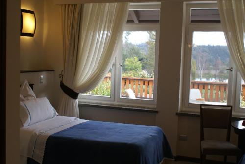 a bedroom with a bed and two windows with a balcony at Villa Baviera, Hotel Baviera Chile in La Máquina