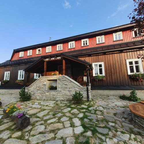 a large wooden building with a stone courtyard in front of it at Stará škola in Dolní Malá Úpa