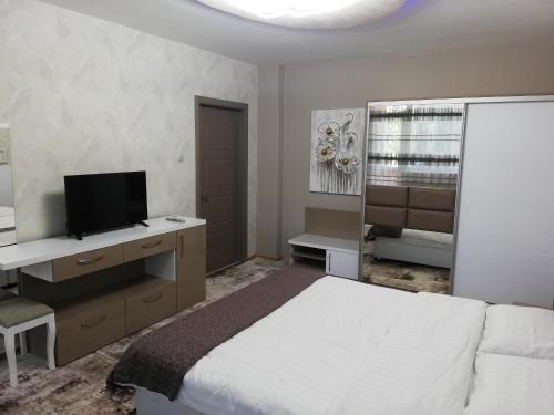 a bedroom with a bed and a desk with a television at Apartment Ani in Veliko Tŭrnovo