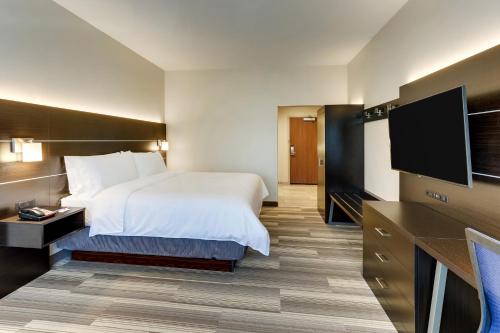 a hotel room with a bed and a flat screen tv at Holiday Inn Express & Suites - Winston - Salem SW - Clemmons by IHG in Clemmons