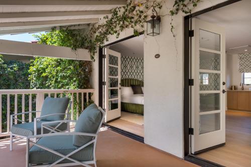 a room with a balcony with two chairs and a bed at The Colony Palms Hotel and Bungalows - Adults Only in Palm Springs