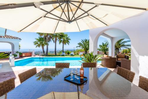 a villa with a swimming pool with a table and an umbrella at Casa Media Luna, Mijas Malaga in Mijas