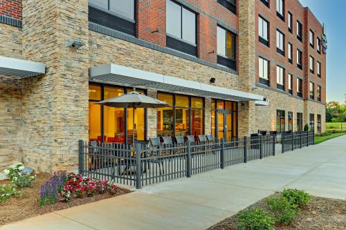a restaurant with an umbrella and chairs in front of a building at Holiday Inn Express & Suites - Winston - Salem SW - Clemmons by IHG in Clemmons