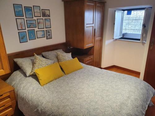 a bedroom with a bed with yellow pillows and a window at Casinha dos Figueirais in Góis