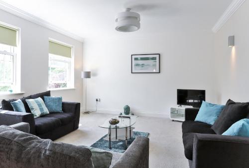 a living room with two couches and a table at KVM - Jubilee Mansions Apartment by KVM Stays in Peterborough