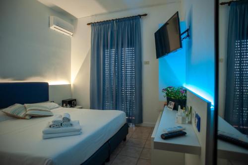Habitación de hotel con cama y TV en Baron Beach Hotel, en Scauri