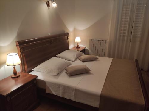 a bedroom with a large bed with two lamps on it at Apartments Drpic in Gabonjin