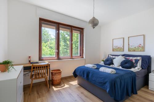 een slaapkamer met een bed, een bureau en ramen bij Kalia Apartmanok in Mindszentkálla