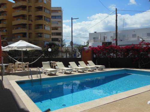 una piscina con tumbonas y sombrilla en Apartamentos Es Cantó en Playa d'en Bossa