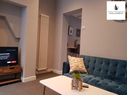 1 Bedroom House by Avenew Management Serviced Accommodation Stoke-on-Trent in the heart of Potteries with Free Parking & WiFi في ستوك أون ترينت: غرفة معيشة مع أريكة زرقاء وتلفزيون