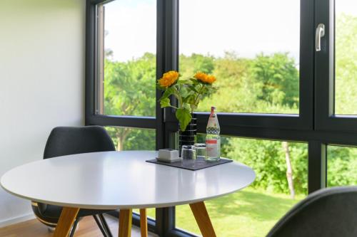 una mesa blanca frente a una ventana con una botella de vino en Das Andere - Gästeapartment, en Kippenheim