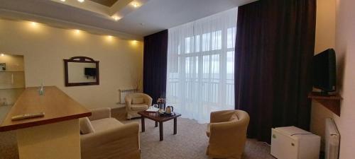 sala de estar con una gran ventana con sillas y mesa en Tropicana Hotel, en Primorsko-Akhtarsk