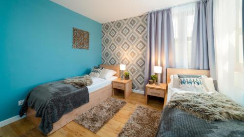 - une chambre avec 2 lits et un mur bleu dans l'établissement HELLO Apartamenty - WIKING przy wyciągu narciarskim, à Karpacz