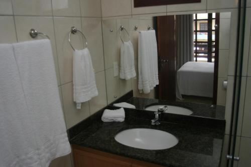 a bathroom with a sink and a mirror and towels at CostaSol Pipa Chalés in Pipa