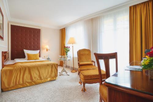a bedroom with a bed and a chair and a desk at Carlsbad Plaza Medical Spa & Wellness hotel in Karlovy Vary