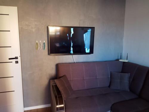 a living room with a couch and a tv on the wall at Ewela in Giżycko