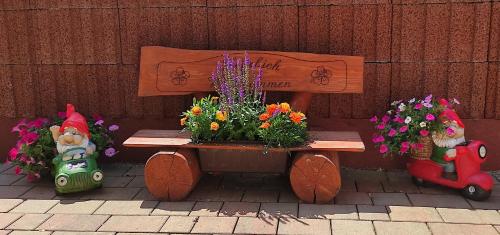 FeWo Am alten Holzplatz في Drübeck: مقعد خشبي عليه زهور بجوار جدار