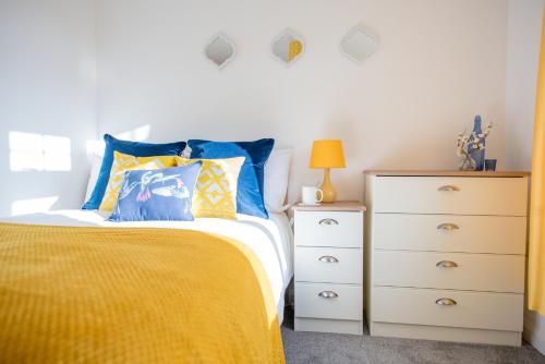 um quarto com uma cama amarela e uma cómoda em KVM - Sunshine Apartment by KVM Stays em Peterborough
