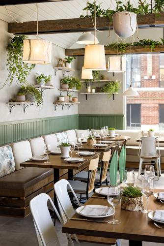 a restaurant with wooden tables and chairs and plants at 1 Hotel Toronto in Toronto