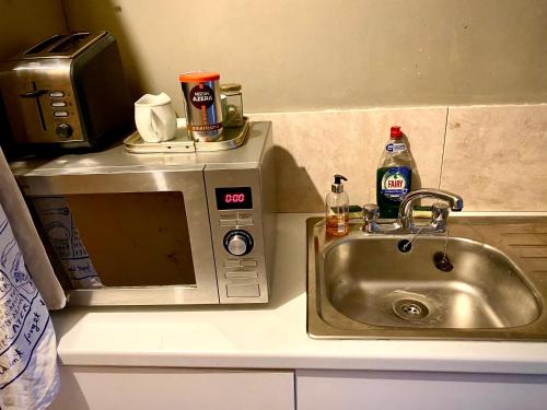 eine Küchentheke mit einer Spüle und einer Mikrowelle in der Unterkunft Spacious King Room with Ensuite in Launton