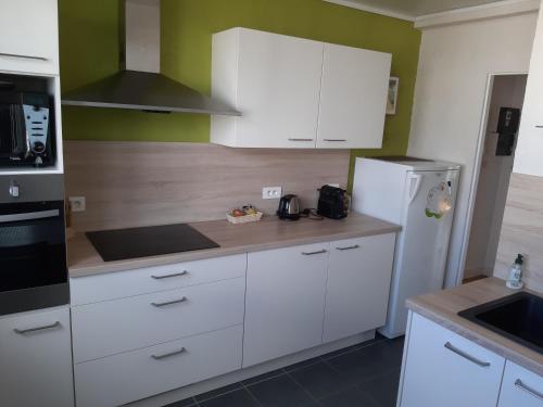 a kitchen with white cabinets and a refrigerator at Appartement lumineux idéalement situé à proximité de musées équipements sportifs salle de spectacle commerces in Caen