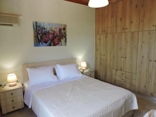 a bedroom with a white bed with two night stands and two lamps at Calm house in Sivros village, Lefkada in Sívros