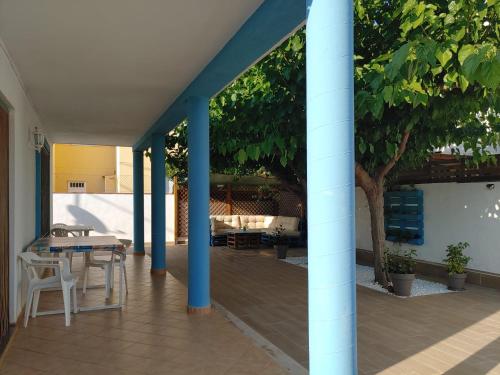 un patio con columnas azules, mesa y sillas en Chalet playa, en Benicarló