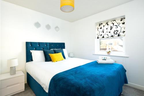 a bedroom with a blue and white bed and a window at KVM - Whitebeam House great location by KVM Stays in Peterborough