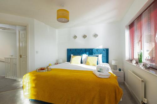 a bedroom with a large bed with a yellow blanket at KVM - Whitebeam House great location by KVM Stays in Peterborough