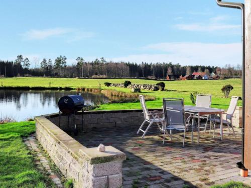 a patio with a table and chairs next to a lake at 6 person holiday home in VITTSJ in Vittsjö