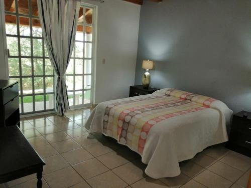 1 dormitorio con cama y ventana grande en Cabaña de Mima Mazamitla, en Mazamitla