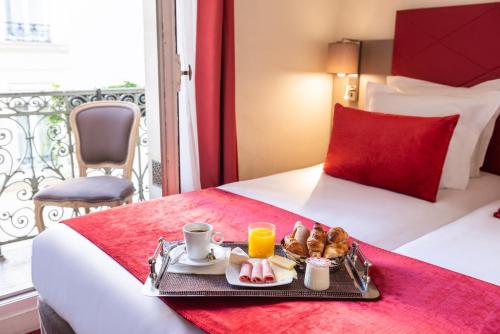 a tray of breakfast food on a bed in a hotel room at Hôtel Aston Paris in Paris