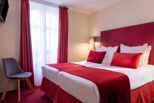 a hotel room with a large bed with red pillows at Hôtel Aston Paris in Paris