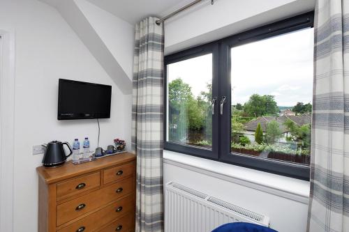 a room with a window with a television and a dresser at Pinewood Cottage Apartment & B&B Inverness in Inverness
